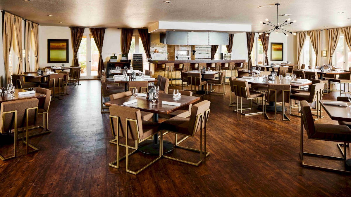 The image shows a modern, upscale restaurant interior with elegant tables and chairs, ready for dining, featuring stylish decor and lighting.