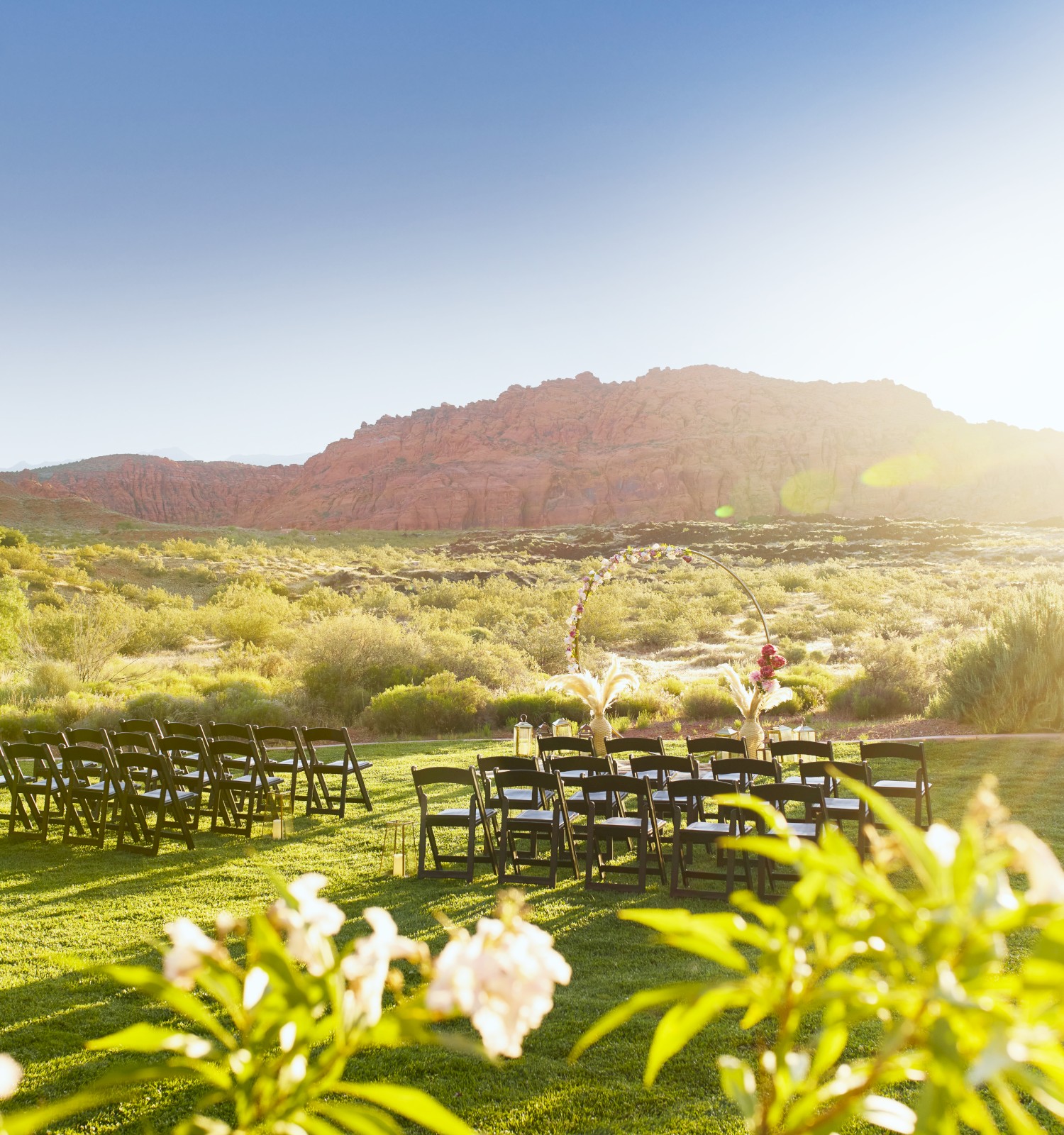 A beautiful outdoor setup featuring rows of chairs facing a scenic view of mountains and greenery under a bright sun.